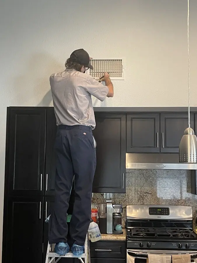 Technician inspecting an air vent during HVAC service in Osage Beach